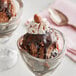 A glass cup with Oringer Premium Fudge dessert topping on chocolate ice cream with whipped cream.