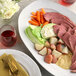 A plate of corned beef and vegetables with a fork and knife.