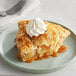 A slice of pie with Oringer caramel dessert topping on a plate with whipped cream.
