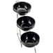 A metal stand with three black bowls on it.