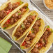 A group of tacos on a wire tray with Cholula Chile Pepper Carne Asada seasoning mix on meat and vegetables.