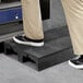 A person standing on a MasonWays black plastic step platform.