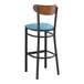 A Lancaster Table & Seating bar stool with a blue vinyl seat and black frame with an antique walnut wood back.