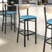 Three Lancaster Table & Seating black bar stools with blue vinyl seats and driftwood backs.