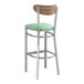 A Lancaster Table & Seating bar stool with a seafoam vinyl seat and wood back.