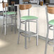 Lancaster Table & Seating Boomerang Series bar stools with seafoam vinyl seats and vintage wood backs at a restaurant counter.