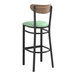 A Lancaster Table & Seating black bar stool with a seafoam green vinyl seat and vintage wood back.