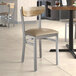 A Lancaster Table & Seating Boomerang Series chair with a wooden seat and back and taupe cushion in a restaurant.