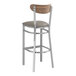 A Lancaster Table & Seating bar stool with a dark gray vinyl seat and vintage wood back.