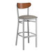 A Lancaster Table & Seating bar stool with a dark gray vinyl seat and wooden back.