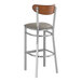 A Lancaster Table & Seating bar stool with a wooden back and dark gray vinyl seat.