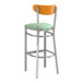 A Lancaster Table & Seating bar stool with a seafoam vinyl seat and cherry wood back.