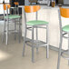 Lancaster Table & Seating Boomerang bar stools with cherry wood backs and seafoam vinyl seats at a restaurant counter.