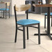 A Lancaster Table & Seating Boomerang Series chair with a blue vinyl seat and driftwood back on a table in a restaurant.