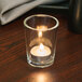 A Sterno Petite Clear Votive Glass candle on a table.
