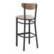 A Lancaster Table & Seating bar stool with a light gray cushion and wood back on a black frame.