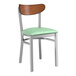 A Lancaster Table & Seating metal chair with a green vinyl seat and wood back.