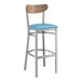 A Lancaster Table & Seating bar stool with a blue vinyl seat and vintage wood back.
