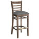 A Lancaster Table & Seating wooden ladder back bar stool with a dark gray vinyl seat.