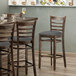 A Lancaster Table & Seating vintage wood ladder back bar stool with dark gray vinyl seat detached.