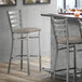 A Lancaster Table & Seating ladder back bar stool with a dark gray vinyl padded seat.