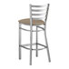 A Lancaster Table & Seating metal ladder back bar stool with taupe vinyl padded seat.