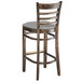 A Lancaster Table & Seating wooden bar stool with a light grey cushion detached.