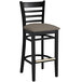 A black Lancaster Table & Seating wood bar stool with taupe vinyl seat and ladder back.