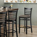 A Lancaster Table & Seating black wood bar stool with a taupe vinyl seat.