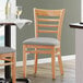 A Lancaster Table & Seating wooden restaurant chair with a light gray vinyl seat