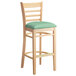 A Lancaster Table & Seating wooden bar stool with a seafoam green cushion on the seat.