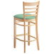 A Lancaster Table & Seating wooden ladder back bar stool with a seafoam vinyl cushion.