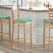 A Lancaster Table & Seating wooden bar stool with a seafoam vinyl seat detached.