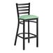 A Lancaster Table & Seating black ladder back bar stool with a seafoam vinyl padded seat.