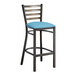 A Lancaster Table & Seating metal bar stool with a blue vinyl cushion.