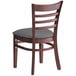 A Lancaster Table & Seating mahogany wood chair with a dark grey vinyl cushioned seat and ladder back.