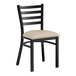 A black Lancaster Table & Seating metal ladder back chair with light gray vinyl padded seat.