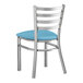 A Lancaster Table & Seating metal ladder back chair with a blue vinyl cushion.