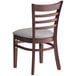 A Lancaster Table & Seating mahogany wood restaurant chair with light grey vinyl seat and ladder back.