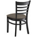 A black Lancaster Table & Seating wood ladder back chair with a taupe vinyl seat.
