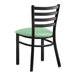 A black metal Lancaster Table & Seating Ladder Back Chair with a seafoam green vinyl padded seat.