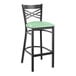 A Lancaster Table & Seating black cross back bar stool with a seafoam vinyl padded seat.