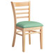 A Lancaster Table & Seating wooden ladder back chair with a seafoam green cushion.