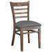 A Lancaster Table & Seating wood ladder back chair with dark gray vinyl seat.
