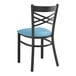 A Lancaster Table & Seating black metal cross back chair with a blue vinyl cushion.