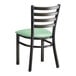 A black Lancaster Table & Seating ladder back chair with a seafoam green cushion.