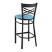 A Lancaster Table & Seating black cross back bar stool with a blue vinyl padded seat.