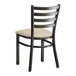 A black metal Lancaster Table & Seating ladder back chair with a light gray cushion.