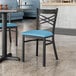 A blue vinyl padded Lancaster Table & Seating chair with black legs at a restaurant table.