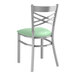 A Lancaster Table & Seating metal cross back chair with a seafoam vinyl seat.
